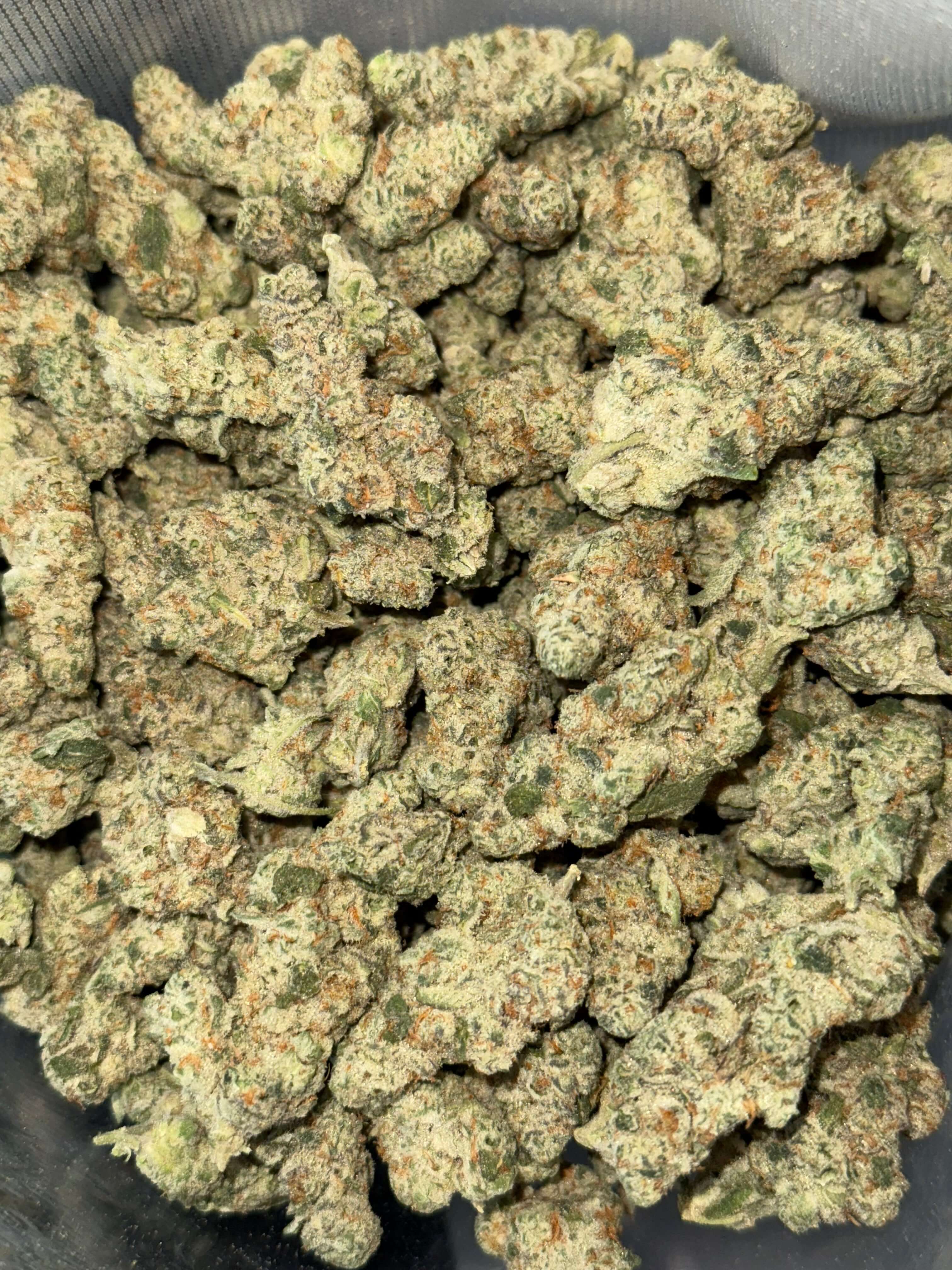 Close-up of fluffy Green Crack cannabis buds, showcasing vibrant green hues and orange pistils. Buy THCA flower online.